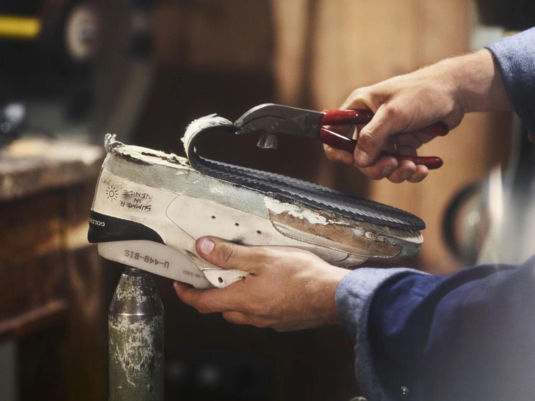 Hands repairing the sole of a low-top sneaker