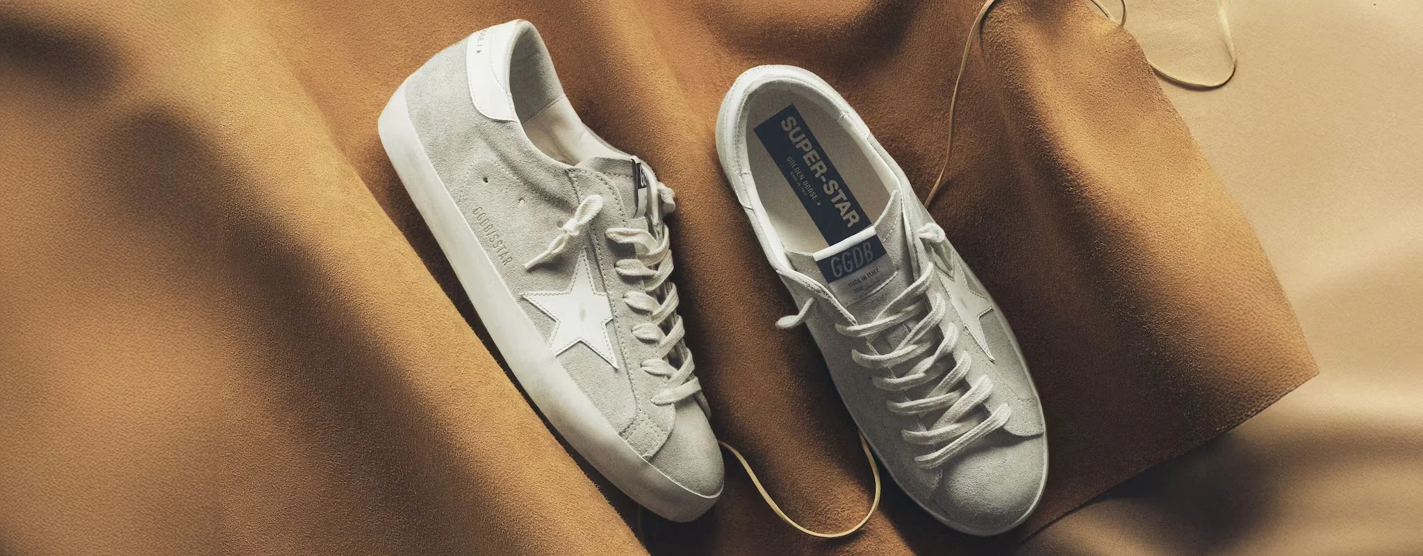 Gray suede low-top sneakers on warm brown fabric
